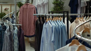 Şık giyim mağazası rafları ve askıları, çeşitli renklerde gömlek seçimleri, şık ve modaya uygun bir moda gösterisi yaratıyor. Boş alışveriş merkezi butiği.