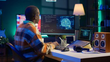 Profesyonel erkek geliştirici masadaki sinirsel ağı yönetiyor, dizüstü bilgisayarda yapay zeka kodu ile çalışıyor. Afrikalı Amerikalı bilişim uzmanı serbest çalışan siber güvenlik geliştiriyor, güvenli veri tabanı yaratıyor. Kamera A.