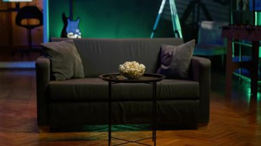 Kanepe ve aperatiflerle dolu rahat bir ev. Sıradan bir film gecesi ya da televizyon izleme deneyimi için hazır. Neon ışıklı ev sinemasında bir kase patlamış mısır.