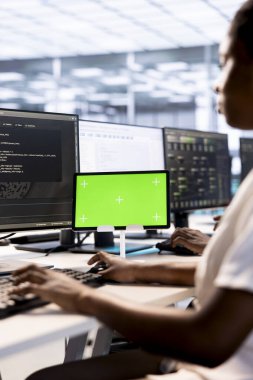 Bilgisayar bilimcisi, veri merkezinin ana bilgisayarlarında arıza olup olmadığını kontrol etmek için yeşil ekran tableti kullanıyor. Bilgi teknolojisi uzmanı sunucu odasındaki hasarları önlemek ve ağları izlemek için model aygıtı üzerinde çalışıyor