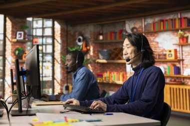 Müşteri hizmetleri çalışanlarından oluşan bir ekip kişisel şirket yazılımında destek biletini takip ediyor. Asyalı çağrı merkezi çalışanı ve Afrikalı Amerikalı iş arkadaşı müşteriyle konuşuyor.