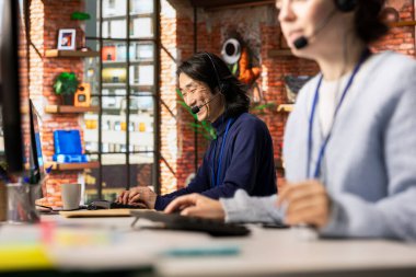 Jolly çağrı merkezi kıdemli ajanı müşteri geribildirimlerini analiz eder, sorunları azaltmak için çalışır. Neşeli Asyalı müşteri hizmetleri çalışanı müşteri ihtiyaçlarını gidermek için problem çözme becerilerini kullanıyor