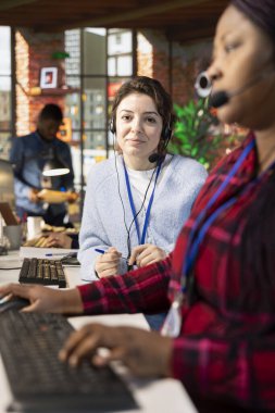 Gülümseyen çağrı merkezinin portresi. Güvertede yeni elemanlara eğitim veren bir uzman. Şirket platformlarının nasıl kullanılacağı konusunda müşteri destek veren dost canlısı bir yönetici