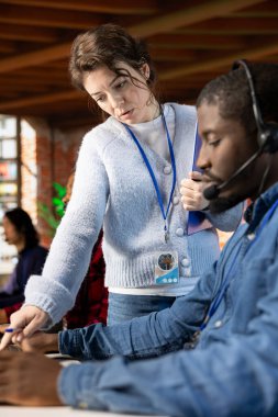 Çağrı merkezi müdürü, Afrikalı Amerikalı stajyere rehberlik ediyor. Sorulara cevap veriyor. Müşteri hizmetleri işyeri. Yeni ajan için oryantasyon oturumları düzenliyor. Kapatın.