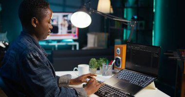 Oturma odasındaki telgraf işçisi yazılım geliştirme ve el kamerası görüntüleri için dizüstü bilgisayar kullanıyor. Aygıt klavyesinde yazan uzaktan çalışan, apartmandaki görevleri çözen, B kamerasını kapat