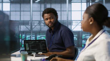 Bilgi işlem uzmanları beyin fırtınası yapıyor, şirket ağ altyapısını koruyor. Sunucu merkezi bilgisayar uzmanlarından oluşan bir ekip sohbet ediyor, optimal sistem performansını sağlıyorlar, kamera A