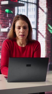 Dikey video yorgunluğu çeken kadın masasında oturmuş dizüstü bilgisayarına bakıyor ve tavan arasında esniyor. Kendini çok yorgun ve yorgun hissediyor. Uzaktan kumandayla uğraşırken yorgunluk, stres ve endişeyle uğraşan kişi