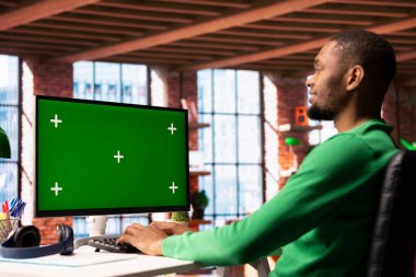 Gülümseyen adam dairede boş vakitlerin tadını çıkarıyor, arkadaşlarına mesaj atmak için yeşil ekran bilgisayar ekranını kullanıyor. Krom anahtar ekran kullanarak sosyal ağ sitesinde arkadaşlarıyla konuşan mutlu kişi