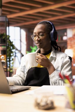 Güne bir fincan kahveyle başlayıp e-posta yazmak için dizüstü bilgisayar kullanan bir tele-işçi. Apartman işyerinde uzaktan çalışan müzik dinleyen, içecekten hoşlanan, klavyede yazan.