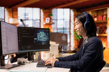 Yapay zekada CTO yöneticisi başlangıç tasarımına odaklanmış uygulamaları tasarlıyor ve tasarlıyor, müzik dinliyor. Kulaklık takan Asyalı teknisyen kod testi ve kalite güvencesi yapıyor.