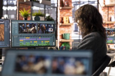 Ajans ofisinden yayın yapan kadın film yapımcısı, video çekimi için kurgu zaman çizelgesi ve renk düzeltmesi sağlıyor. Teknik güdümlü çalışma alanı dijital bir iş akışı sergiliyor.