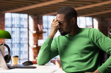 Evdeki adam uykusuzluktan ve uykusuzluktan bitkin düşmüş ve acı çekiyor. Bitkin düşmüş Afrikalı Amerikalı. Ağrıdan, kapanan gözlerden etkilenmiş, stresli.