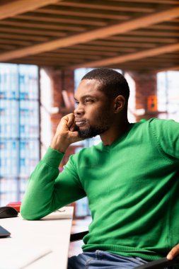 Ofis masasında iş projesiyle ilgili fikirler bulmakta zorlanan bir adam. afrikalı amerikan uzaktan kumandalı şaşkın çalışanı apartman dairesinde araştırma yapıyor, görevleri nasıl çözeceğini düşünüyor.