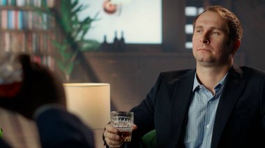 Seçkin sosyal kulüpte bir bardak viski içip servetini ikiye katlama fırsatını düşünen zengin varis. Alkol yudumlayan zarif üst sınıf milyarder beyefendi. Kamera B.