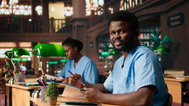 Tıp asistanı kütüphanede yeşil bir lambanın altında kitap okuyor, tıbbi yöntemler hakkında araştırma yapıyor ve sınavlara hazırlanıyor. Genç adam kariyerine bağlılığını gösteriyor. Kamera A.