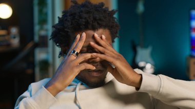 Afrika kökenli Amerikalı bir adam migren ve hastalıktan muzdarip, evdeki kanepede oturuyor ve kendini çok yorgun hissediyor. Endişeli genç yetişkin acıyla boğuşuyor, yorgun ve endişeli adam. Kamera B.