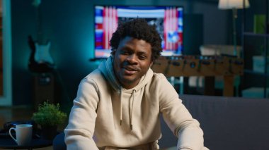 Siyah uzaktan kumandalı işçi, neon ışıklarla dekore edilmiş şık dairesinde dizüstü bilgisayarında gezinirken esnekliğin ve konforun tadını çıkarıyor. Rahat bir evde mükemmel bir şekilde yakalanmış serbest çalışma. Kamera A.