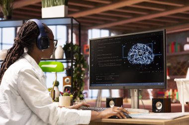 Kulaklık takan programcı evdeki bilgisayarı kullanarak insan beyni simülasyonu yapıyor. IT uzmanı müzik dinliyor ve evde yapay zeka ile çalışıyor.