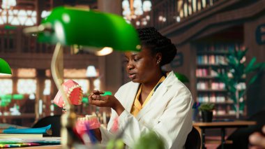 Afrika kökenli Amerikalı öğrenciler diş hekimliği tezi için dişleri inceliyor, kampüs kütüphanesinde stomatoloji araştırmalarında birlikte çalışıyorlar. Erkek ve kadın kariyerlerine hazırlanıyorlar. Kamera B.