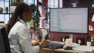 Merkez ofisteki mühendis UI 'ye bilgisayar monitöründe bakıyor, programlama kodunu yazıyor ve çalıştırıyor. IT çalışanının modern apartmanda kod yazıp test etmek için kodlama uygulaması kullanırken çekilmiş görüntüsü, kamera B