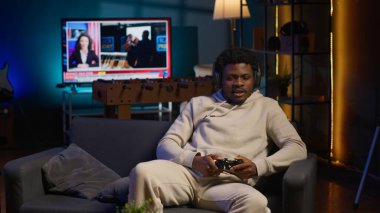 Evinde video oyunu oynayan neşeli bir adam işten izin gününün tadını çıkarıyor. Siyah oyuncu oyun konsolunda online çok oyunculu atıcılarla savaşıyor. Kamera A.