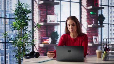 Gülümseyen bayan internet siparişini öderken kartını tutuyor. Ev ofisteki tabletle para aktarıyor ve alışveriş yapıyor. Kredi bakiyesini kontrol ettikten sonra memnun kadın alışverişi. Kamera B.