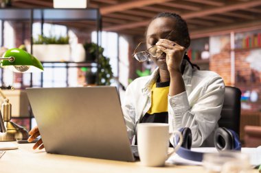 Dairesinde çok çalışan, gözlük takan, dizüstü bilgisayarda çok çalıştıktan sonra gözlerini rahatlatmaya çalışan bir kadın. Uzaktan çalışan, göz yorgunluğu çeken, evden çalışırken aşırı uyarılmış biri.