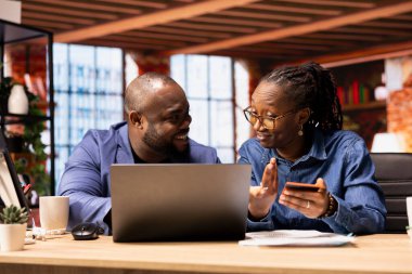 Merkez ofisteki sorumlu çift dizüstü bilgisayarda aile finansmanı düzenliyor, kart numaralarını çevrimiçi girerek ortak hesap giderlerini takip ediyorlar. Çocukları için para transferi onaylanıyor.