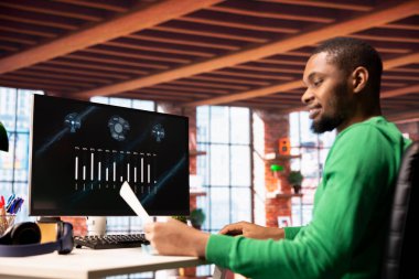 Şirketin gelirini ve giderlerini gösteren bilgisayar ekranında finansal uygulama UI kullanarak gülen adam. Apartmandan çalışan muhasebeci bilgisayar ekranı kullanarak yıllık kâr değerlendirmesi yapıyor