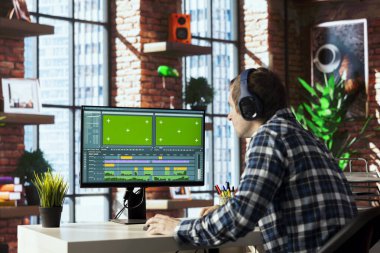 Video editörü İHA çekimlerinin bölümlerini buduyor, tanıtım videoları üzerinde çalışıyor. Film parçalarını birleştiren, yeşil ekranda profesyonel yazılım kullanarak düzenleyen kameraman