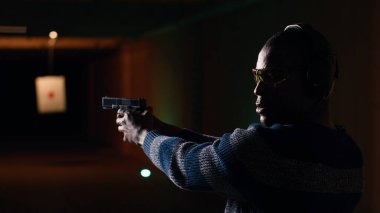 Mutlu atış poligonunun portresi. Müşteri silah dolduruyor, hedef vuruyor, eğleniyor. Zemin tesisinde neşeli bir adama yakın durun. Silah doldurun. Koruyucu gözlük takın.