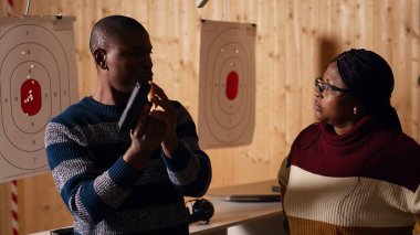 Galeri çalışanı müşterilerle buluşuyor, onları selamlıyor, silahı güvenli bir şekilde nasıl doldurulacağını gösteriyor. Atış menzili uzmanı müşterileri karşılıyor, tokalaşıyor, silah kullanmayı öğretiyor, kamera B