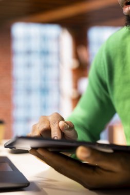 Oturma odasında sosyal medya iletileri yazmak için tablet kullanan ve içerik üreten bir adam. Dijital cihaz kullanarak sosyal medya bağlantısını izleyen Afrikalı Amerikalılara yakın çekim