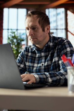 İç ofis masasındaki adam dizüstü bilgisayardaki belgeleri düzenler, raporları ve dosyaları günceller, metin yazar, paragrafları biçimlendirir, resimler yerleştirir, değişiklikleri kaydeder, dosya dizinleri içindeki dijital belgeleri yönetir