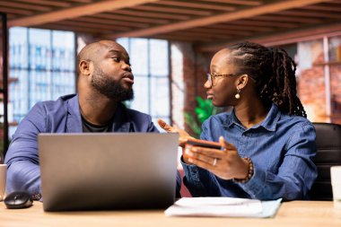 Genç çift, bir şey almadan ya da ödemeden önce mali bakiyeyi kontrol etmek için bir kart kullanıyor. Afrikalı Amerikalı erkek ve kadın internet alışverişi yapıyor..