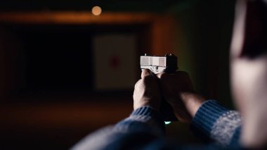 Atış poligonunda ateşli silah kullanan bir adam hareket halindeki hedefin sonuçlarına bakıyor. Rekabetçi atış sporu, keskinleştirme becerileri, hedef tahtası ve B kamerasından alınan kontrol puanlarına yakın durun.