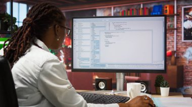 Merkez ofisteki mühendis UI 'ye bilgisayar monitöründe bakıyor, programlama kodunu yazıyor ve çalıştırıyor. IT çalışanının modern apartman, kamera A 'da kod yazıp test etmek için kodlama uygulamasını kullanırken görüntüsü.