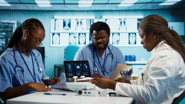 Uzman danışmanlık ve tedavi tavsiyeleri sağlamak için teşhis araçları ve verileri kullanan tıp uzmanları. Profesyonel bir sağlık ortamında bir grup asistan. Kamera B.