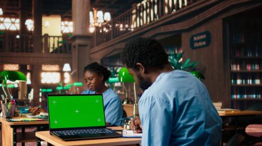 Siyahi tıp öğrencisi kütüphanedeki dava dosyalarını fotokopi ekranının yanında inceleyerek, tıbbi uygulamalar üzerine bir ders ya da çalışma oturumuna hazırlanıyor. Tıp fakültesi öğrencisi kariyer için öğreniyor. Kamera A.