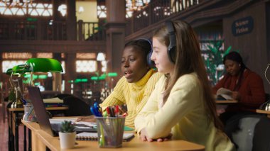 Kütüphanedeki çevrimiçi kursa katılan kızlar bir okul projesini tamamlamak için öğretmenleriyle canlı video webinar 'ına katılıyorlar. Bilim adamları video dersi üzerinden bir ödev üzerinde çalışıyorlar. Kamera A.