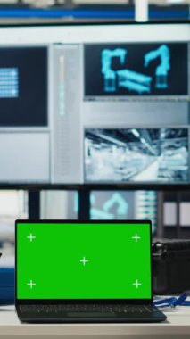 Robot silah üreten güneş panelleri performansını izlemek için fotovoltaik fabrikasında kullanılan dikey video yeşil ekran laptop. Güneş enerjisini incelemek için kullanılan boş sanayi merkezindeki krom anahtar defter.