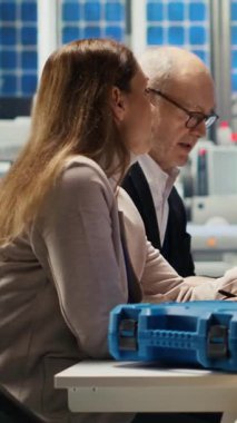 Dikey video mühendisleri güneş paneli montaj hatlarının ayrıntılı şemalarını, üretim planlarını ve verimlilik için bileşen yapılandırmalarını inceliyor, yeni prototipler için dokümanları özetliyor