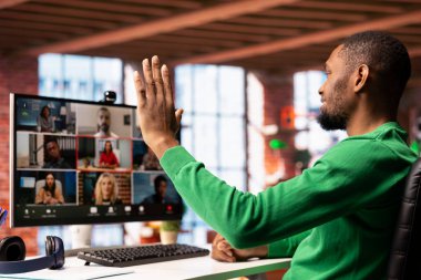 Uzaktan kumandalı ofis çalışanı çevrimiçi video görüşmesi sırasında meslektaşlarını selamlıyor, bilgisayar ekranına bakıyor. Video konferansı sırasında apartman çalışanlarını karşılayan iş adamı