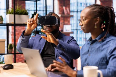 Serbest çalışan çift, gelişmiş teknolojiyle uzaktan kumandalı bir işte çalışıyor. Genç adam, VR kulaklığıyla 3 boyutlu simülasyonları keşfediyor. Modern serbest meslek yaşamında yapay zeka, metaevren ve yenilik..