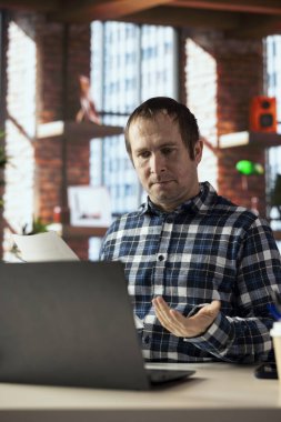 Ev ofisinin masasında dizüstü bilgisayar kullanan, sözleşme hazırlayan, şartları özetleyen, yasal metni inceleyen, belgeleri kaydeden, son sürümleri dış ortaklara gönderen bir adam.