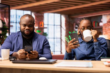 Siyahi erkek ve kadın işçiler, günlük serbest işlerini, ev ofis verimliliğini çözmeden önce e-postalarına cevap verir ve sosyal güvenlik numaralarını kontrol ederler. Cep telefonu kullanan genç çift..