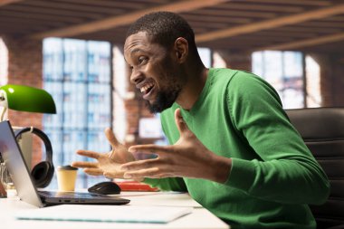 Ofis masasındaki neşeli adam bilgisayar ekranına bakıyor, iş başarısından çok memnun. Kendinden geçmiş uzaktan kumanda çalışanı iş yerinde olumlu sonuçlara tepki veriyor, defter ekranına bakıyor