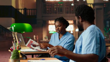 Geleceğin hemşireleri bir üniversite kütüphanesinde anatomi dersi alıyor, dersleri gözden geçiriyor ve sınavlara hazırlanıyor. Siyahi tıp fakültesi öğrencileri tıp eğitimi için birlikte çalışıyorlar. Kamera B.