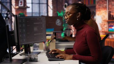 Bilgi İşlem çalışanı kodlama görevlerinde yardım almak için büyük dil modeli uygulaması kullanıyor. AI LLM sohbet robotu PC GPT yazılımı ile iletişim kuran kadın yazılım geliştirme işyeri, kamera B