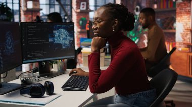 Başlangıçta yapay zeka algoritmasını programlayan programcı, otomasyon ve veri güdümlü karar verme mekanizmasını geliştirmek için makine öğrenme modellerini rafine ediyor. Ofiste kodlama platformu kullanan kadın, kamera A